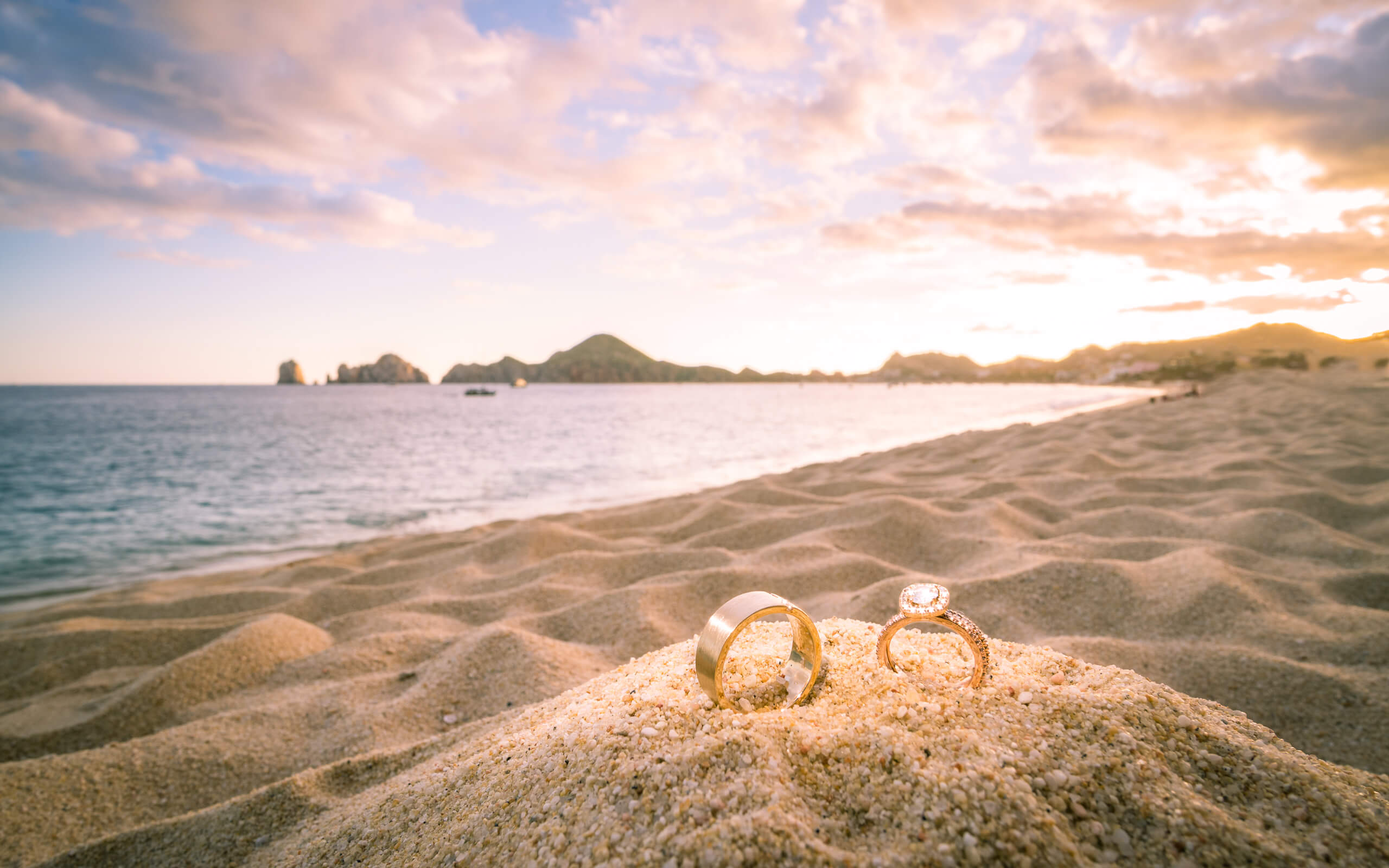 Photo Portfolio. Feature LIFELIGHTLENS Image of rings in the Cabo San Lucas sand during a destination wedding