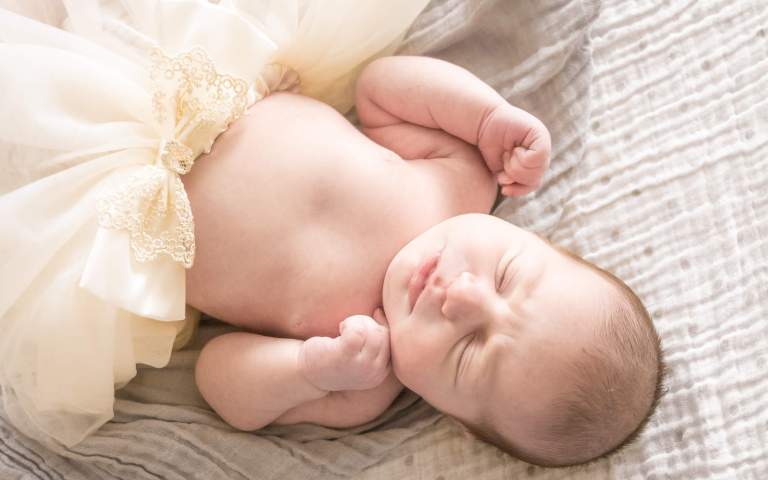 Newborn Photography. A little baby girl lies with her eyes closed