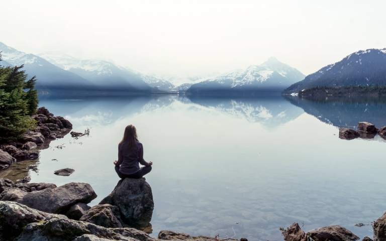 Adventure Photos. Featured LIFELIGHTLENS image of a woman meditating by a still Garibaldi Lake